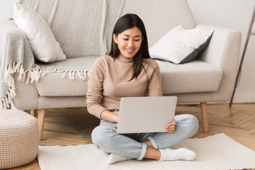 Teen asian girl networking on laptop, sitting on floor