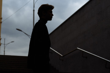 dark outline of a man, siluet, with his head bowed, on the steps, concept