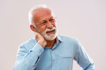 Portrait of senior man who is having pain in neck.