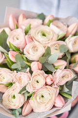 Bunch pale pink tulips and ranunculus flowers with green eucalyptus. The work of the florist at a flower shop.
