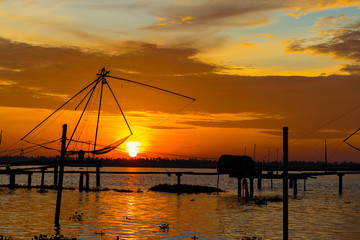 Fototapeta na wymiar Warm sunset on the backwaters of Kumablangi, Cochin, India, with fishing nets on the foreground.