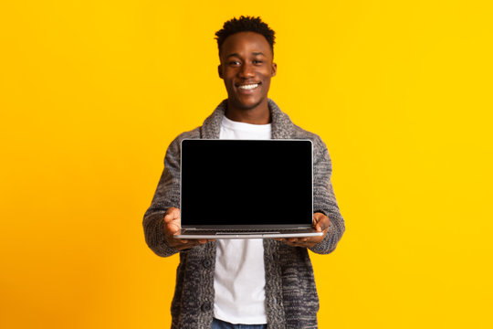 Young excited joyful african man holding in hands laptop