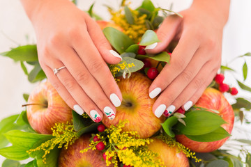 Close-up of bridal manicure. Hands laying on the wedding bouquet. Engagement ring on her finger.