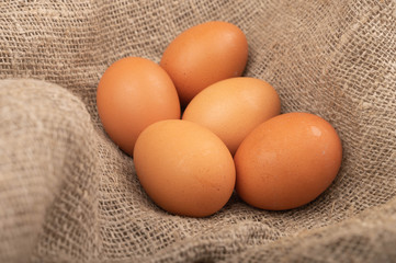 Chicken eggs on a background of rough homespun fabric. Homemade preparations, rustic treats. Close up.