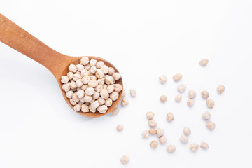 Chickpeas on wooden spoon on  white background. Top view.