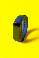 Classic blue fitness tracker on bright yellow background. Fitness bracelet for sports training. Healthy lifestyle.