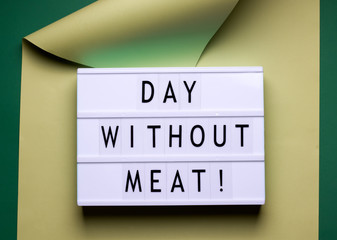on a green background there is a lightbox with the text wrapped in paper. International Day Without Meat concept