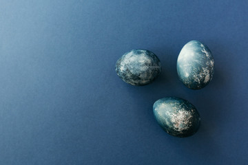 Beautiful group ombre blue Easter eggs with quail eggs and feathers on a blue background. Easter concept. Border eggs. Copy space for text