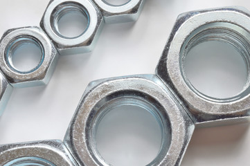 New, chrome new nuts of different sizes on a white background.