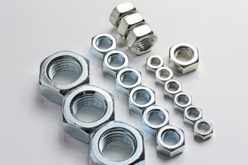 New, chrome new nuts of different sizes on a white background.