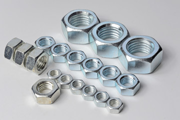 New, chrome new nuts of different sizes on a white background.