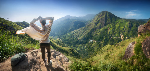 Happy woman traveler enjoying early morning beautiful nature on background of mountain peak 
