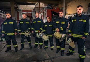 Fototapeta premium Portrait of firefighters standing by a fire engine.