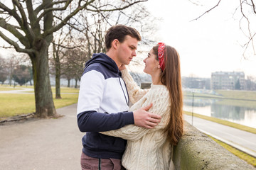 Naklejka premium Young couple in love outdoor. Cute couple of young people is walking in spring park. Happy guy and girl. They are looking at each other