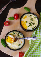 Baked shirred eggs with cheese served with basil