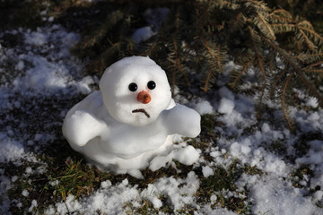 Snowman is melting in the sun. Thaw, warm winter, early spring, global warming, climate change....