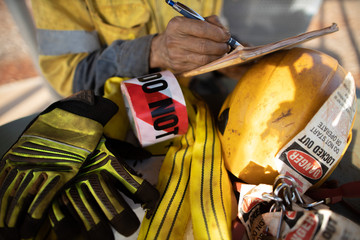 Rigger inspector high risk worker   inspecting checking yellow three lifting sling with red danger...