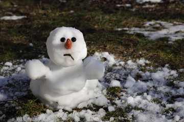 Snowman is melting in the sun. Thaw, warm winter, early spring, global warming, climate change....