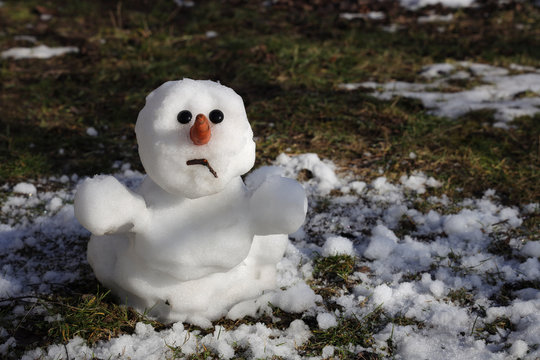 Snowman is melting in the sun. Thaw, warm winter, early spring, global warming, climate change. Spring background.