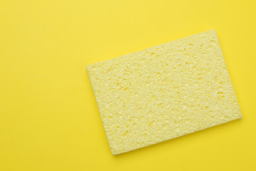 The concept of minimalism. Yellow sponge for washing dishes on a bright yellow background. top view. place for text