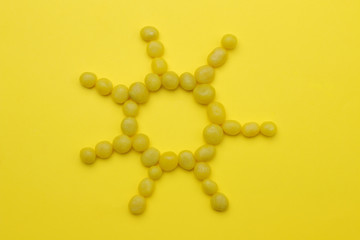 The concept of minimalism. The sun from sweet yellow sweets on a bright yellow background. top view.