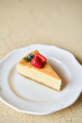 Closeup piece of delicious cheesecake with strawberry and mint leaves on white plate.