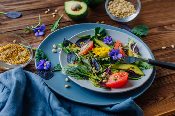 Fresh healthy salad with edible flowers on rustic wooden background