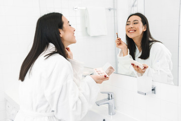 Obraz na płótnie Canvas Woman indoors at home in bathroom apply makeup.