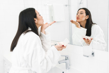 Fototapeta premium Woman indoors at home in bathroom apply makeup