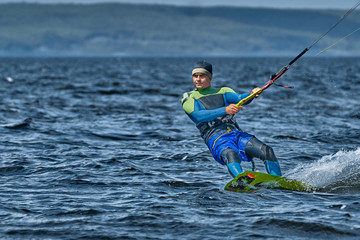 A male kiter slides on the surface of the water. Splashes of water fly apart.