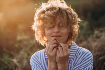 woman with curls coquettishly covers her face with hair. Soft selective focus.
