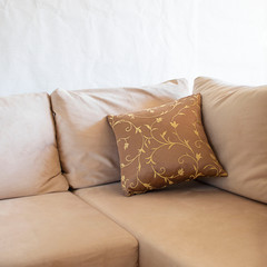 Beautiful brown pillow on light sofa on the background of white wall. Decoration in living room interior. Square with copy space