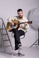 A man in a shirt with an acoustic guitar.
