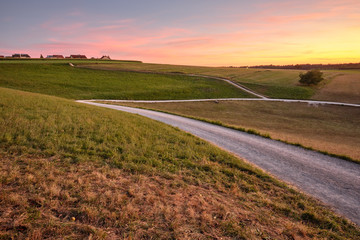 Beautiful countrsyside landscape during sunset with fields, meadows, gravel roads and some houses on the horizon. Seen in late summer in Franconia / Bavaria, Germany near Kalchereuth