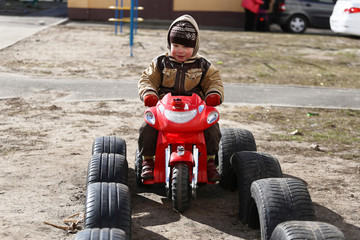 child rides a toy car in spring