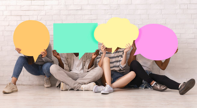 Group of teen friends covering faces with colorful speech bubbles