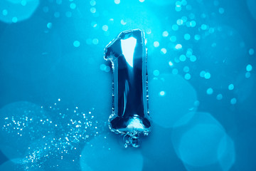 Silver Number Balloons with number One 1. Holiday Party Decoration or postcard concept with top view on blue background with bokeh lights