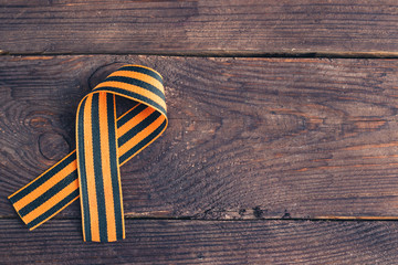 Georgievsk ribbon Russian symbol on a dark wooden background. Holiday card for the holiday of May 9.