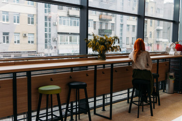 red-haired girl sitting alone in a cafe, loneliness