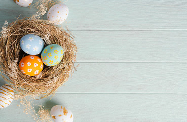 Happy easter, Easter painted eggs in nest on wooden rustic table for your decoration in holiday. Top view with copy space.