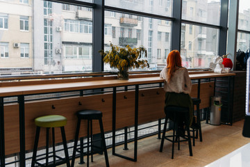 red-haired girl sitting alone in a cafe, loneliness