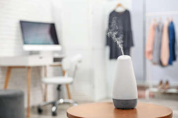 Aroma oil diffuser on wooden table indoors, space for text. Air freshener