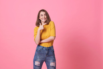 Fototapeta premium Beautiful healthy young woman smiling with his finger pointing and looking at on light pink banner background with copy space.
