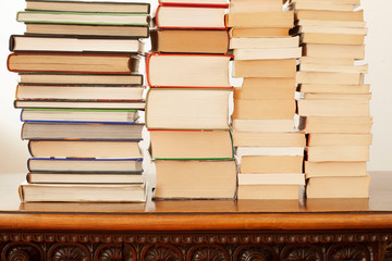stack of piled books rest on a wooden table with copy space for your text