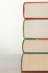 stack of piled books rest on a wooden table with copy space for your text