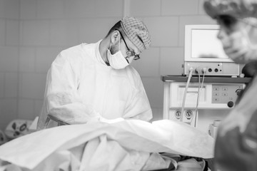 Surgeon performing surgery on breasts in hospital operating room. Surgeon in mask wearing surgical...