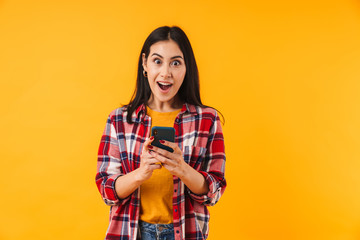 Image of surprised attractive woman in plaid shirt typing on cellphone