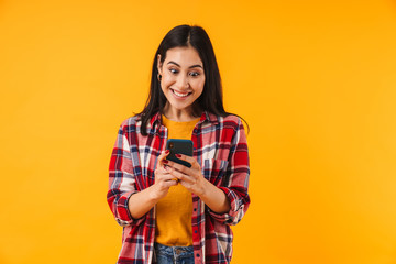 Image of excited attractive woman smiling and typing on cellphone
