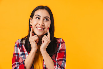 Image of happy woman smiling and pointing fingers at her cheeks