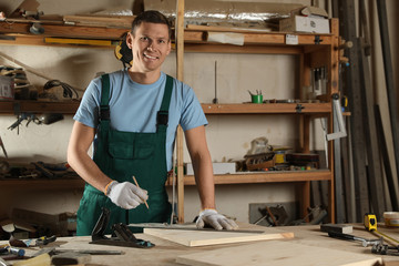 Professional carpenter measuring wooden board in workshop